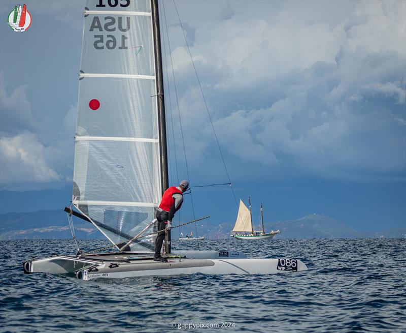 A Class Cat Worlds at Punta Ala - US Classic sailor Bob Webbon, USA 165, looks at the schooner and the impending storm photo copyright Gordon Upton / www.guppypix.com taken at Centro Velico Punta Ala and featuring the A Class Catamaran class