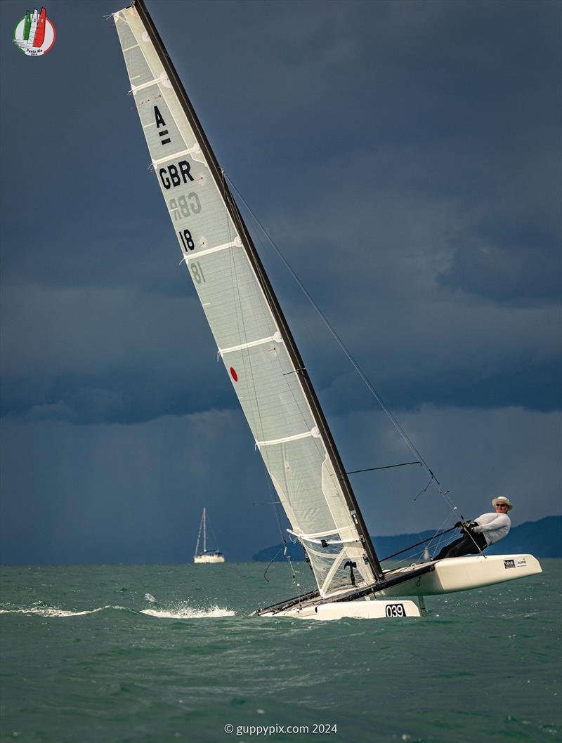 A Class Cat Worlds at Punta Ala - GBR Classic A-Cat sailor and National Champ, Hugh MacGregor GBR 18, having fun as he runs from the storm photo copyright Gordon Upton / www.guppypix.com taken at Centro Velico Punta Ala and featuring the A Class Catamaran class