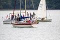 Alicat at anchor while members of Lindsay Tosh's family prepare to scatter his ashes and drop their flowers onto the sea; two of the members' flotilla boats nearby © Margaret Purkis