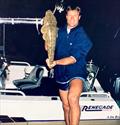 ET as a teenager standing on a wharf with my 5.2m white centre console tied up holding a flathead