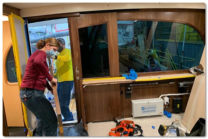 Interior Installer Ann Marie Kavanagh and Interior Trim Leadman Guido Monroy carry a stateroom door into the salon of a Viking 68 on Line 2. - photo © Viking Yachts