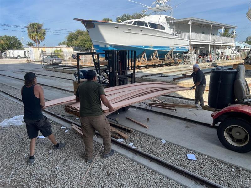 Hull #12 - Flipper, Miguel, and Sal unloading planking - photo © Michael Rybovich & Sons