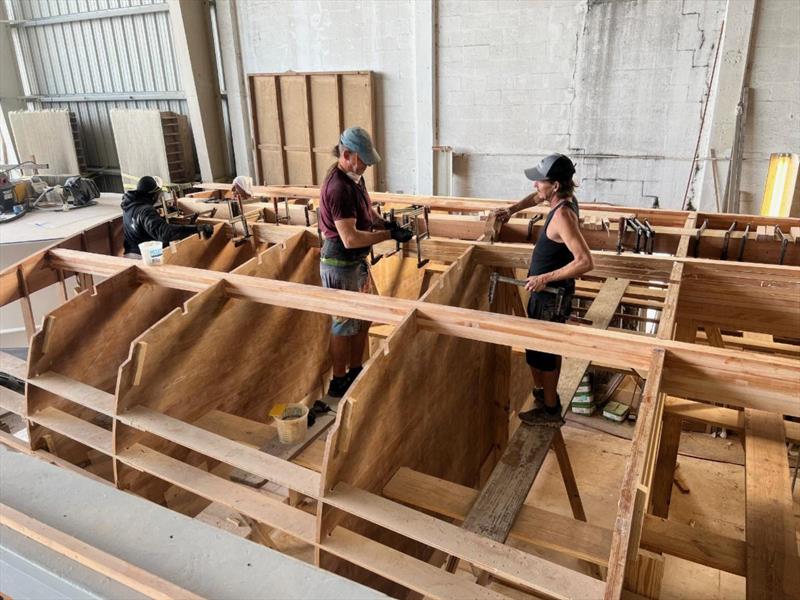 Hull #12 - Jermaine, Scott and Flipper laminating bottom stringers - photo © Michael Rybovich & Sons