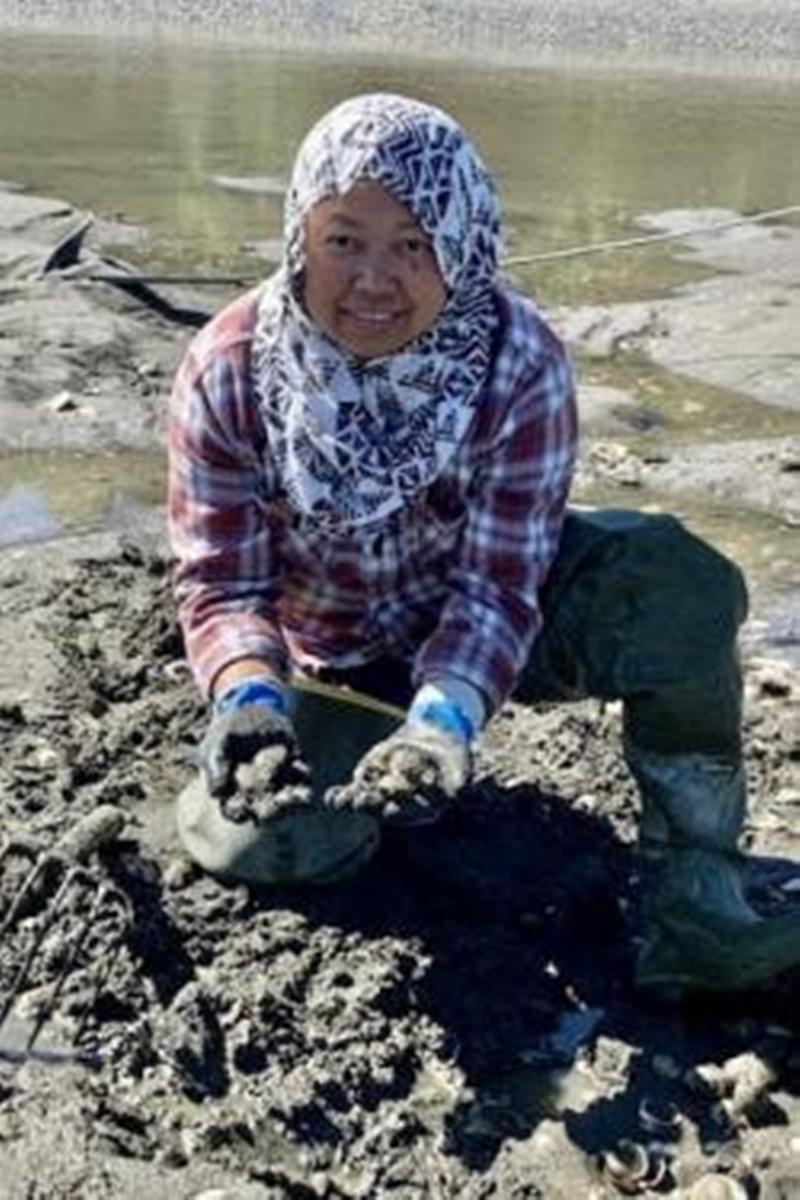 Aisha kneels on the mudflats after digging for oysters to supply seafood markets with sustainable shellfish photo copyright Aisha Prohim taken at 